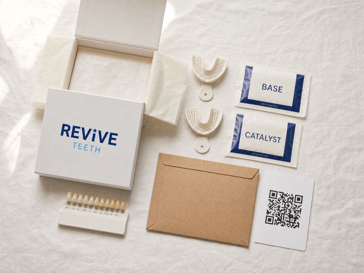 The Revive impression kit photographed from above, with the box, upper and lower trays, base and catalyst putty packets, a shade matching card, a prepaid return mailer, and the card with the QR code to the video.