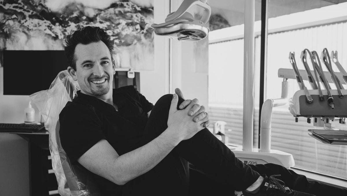 Dr. Brandon Turley sitting back in a dental chair in his practice, smiling.